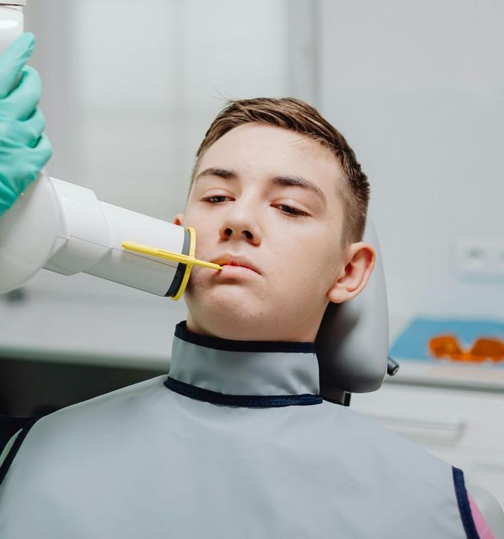 A young man is getting an x-ray of his teeth in a dental office.