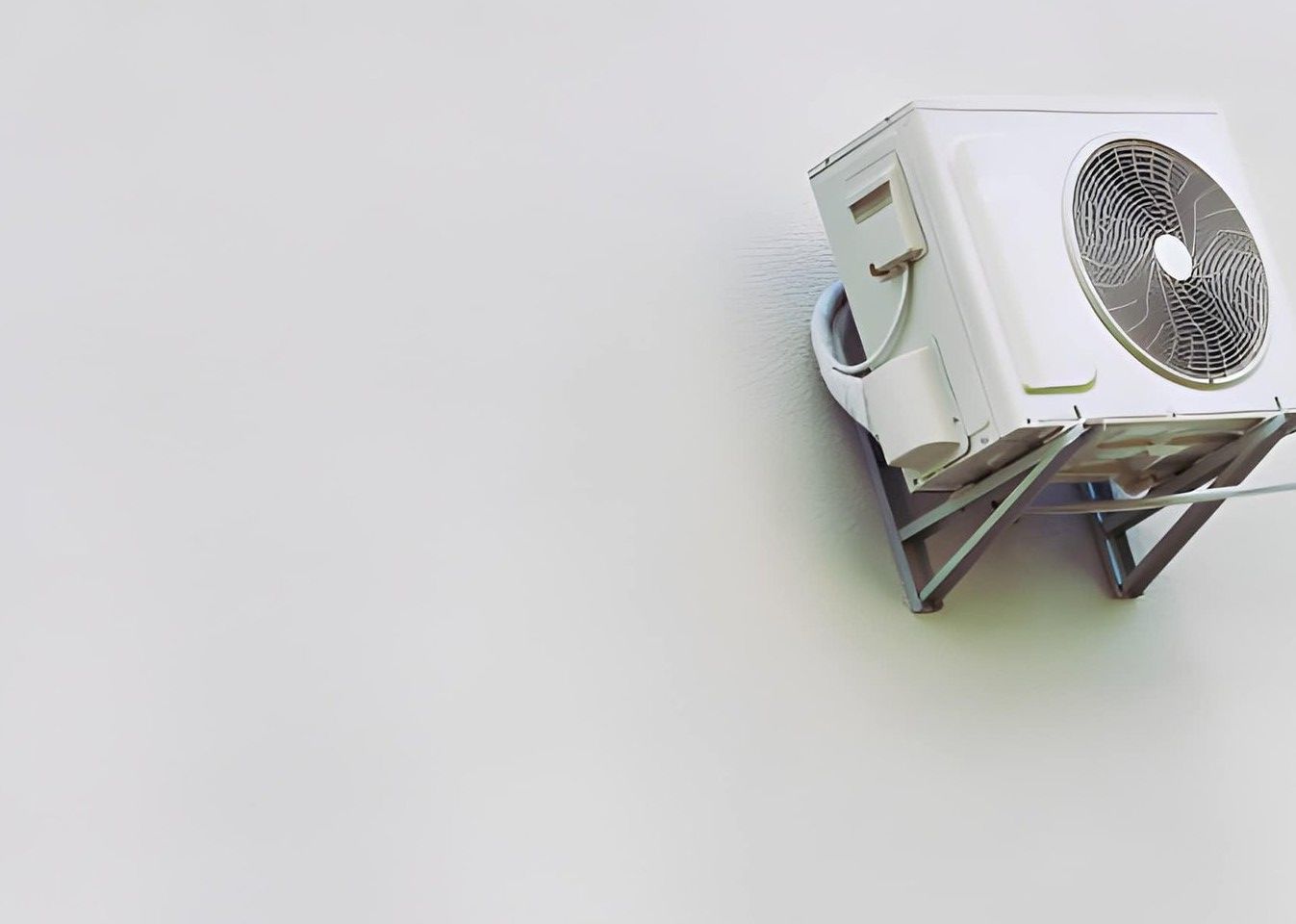 The corner of a white building with a blue sign, viewed from above looking down at patterned gray stone tile flooring.