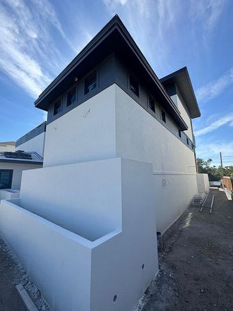 A narrow, white-walled corridor with gray tiled floors, featuring two windows with blue decorative grilles and one skylight.