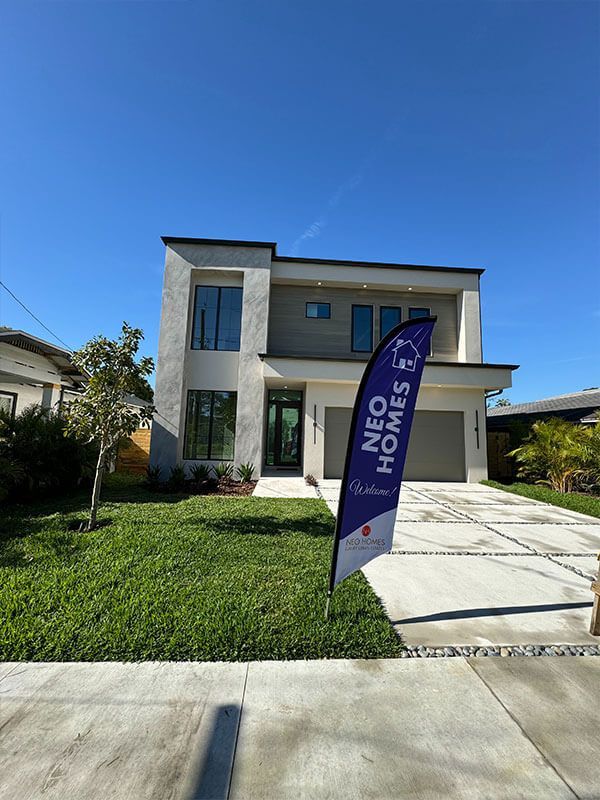 A modern two-story home with a light-colored stucco exterior, a gray garage, and a 