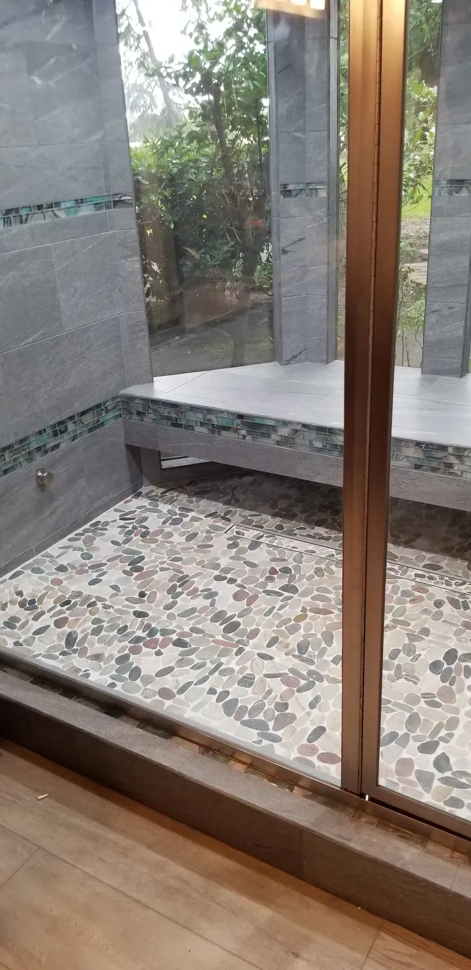 Courtyard view through a glass door, with a stone bench and pebble floor outside