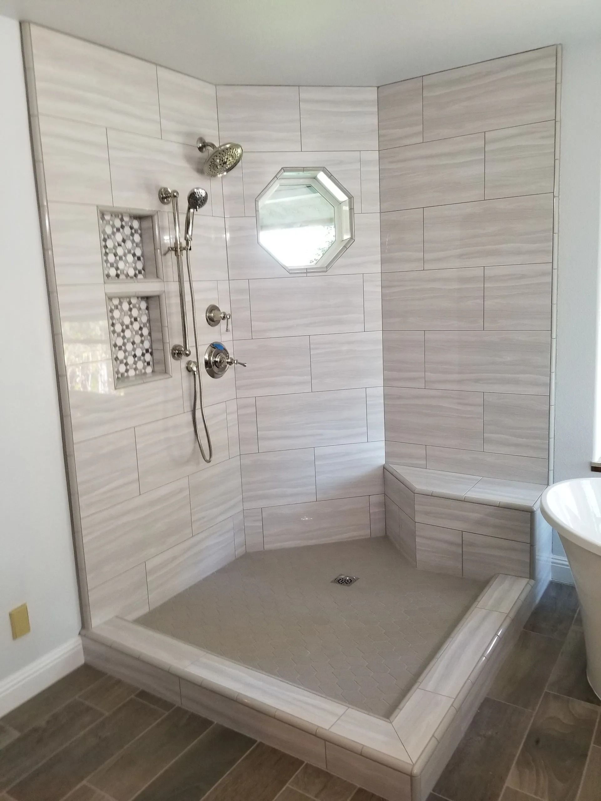 Walk-in shower with white tile, built-in bench, and handheld showerhead in a bathroom