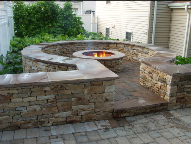 “Finished stone patio and low masonry wall surrounding a backyard outdoor living area after a masonry service in Friendswood, TX”