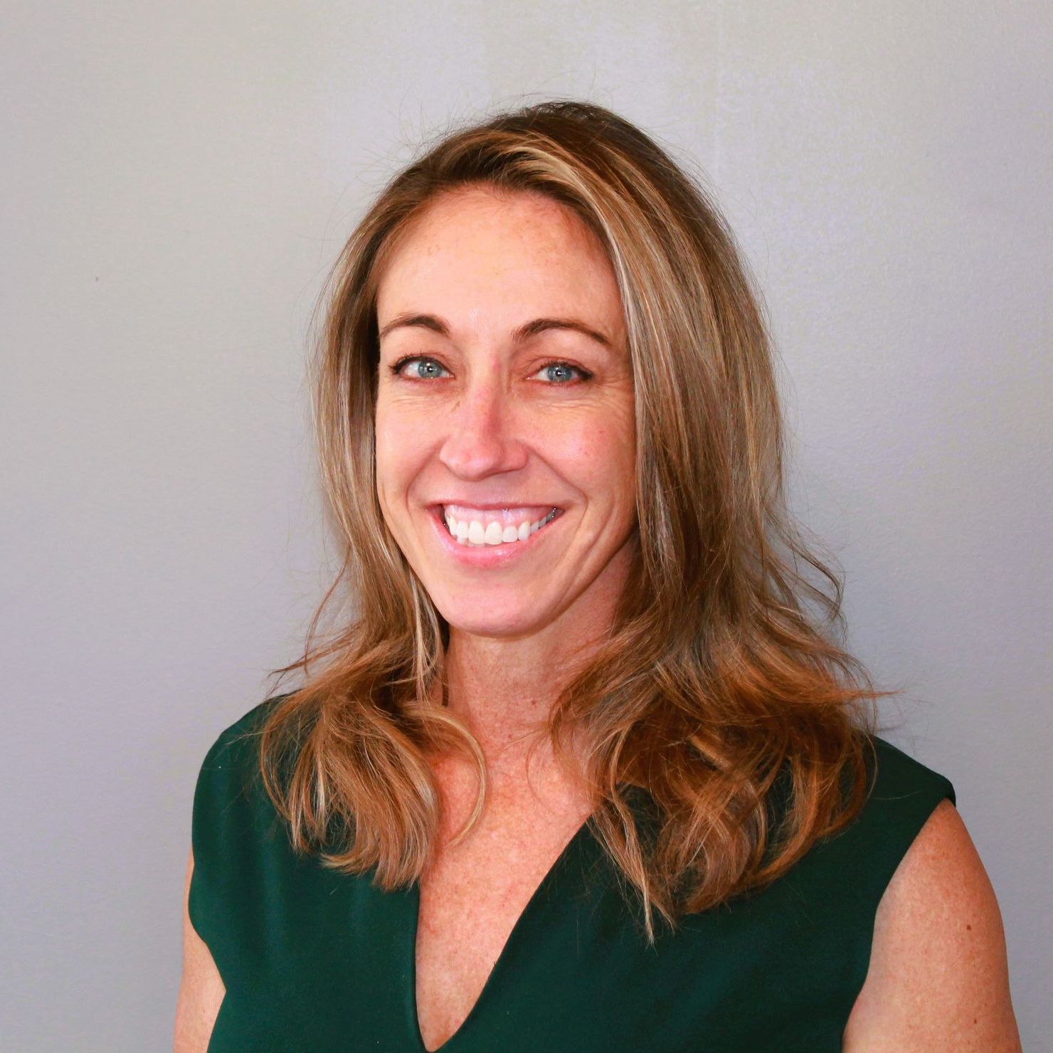 A woman in a green shirt is smiling for the camera.