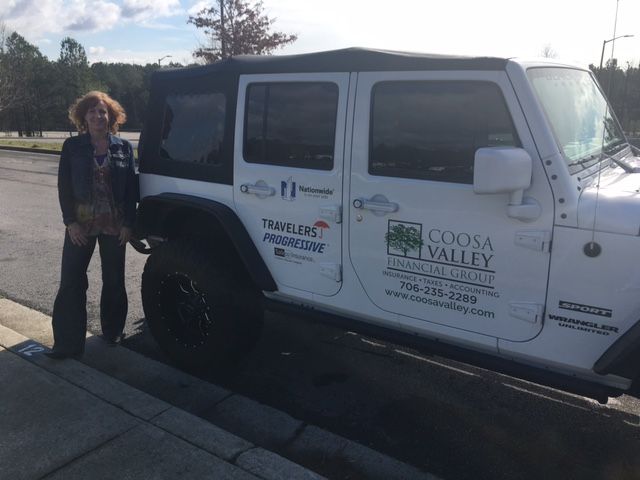 A woman standing next to a white jeep that says goose valley