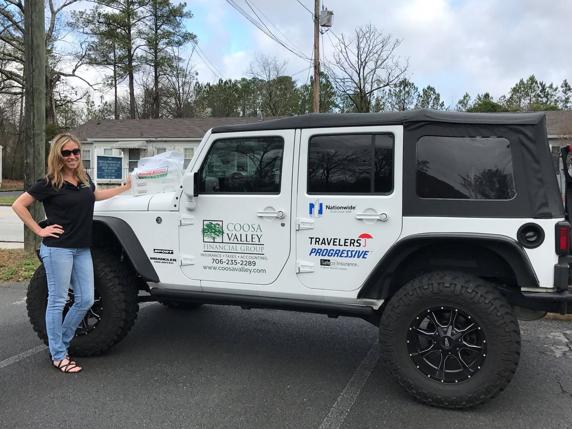 A woman is standing next to a white jeep that says tommy bahama on the side.