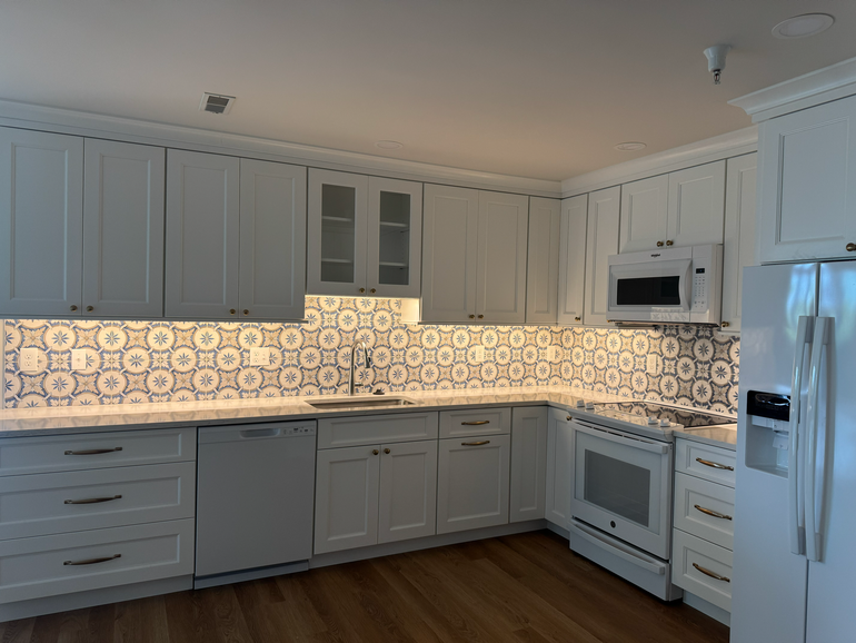 Modern kitchen with large island, brick base, dark cabinets, and a unique light fixture.