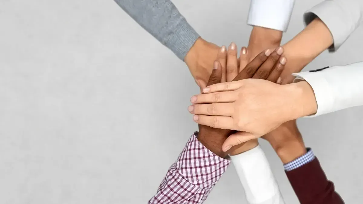 A group of people are putting their hands together.