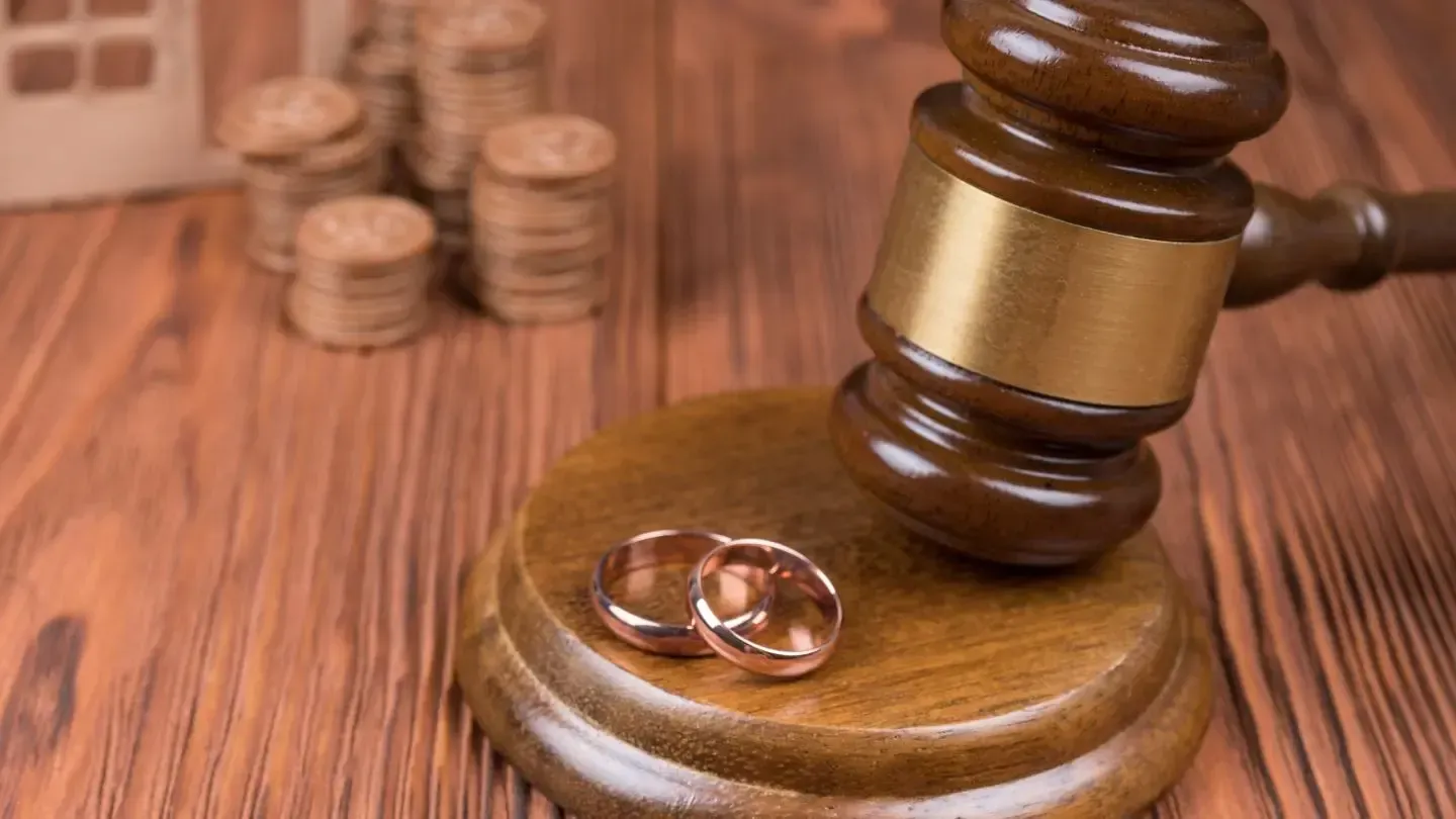 A pair of wedding rings sitting on top of a wooden judge 's gavel.