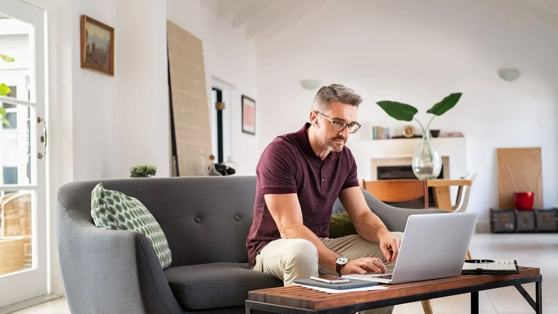 A man is sitting on a couch using a laptop computer.