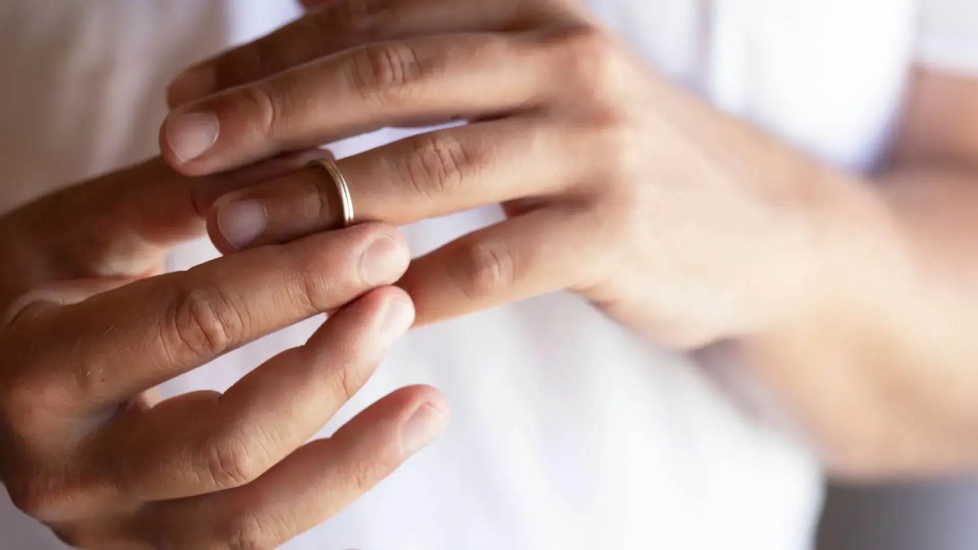 A man is putting a wedding ring on his finger.