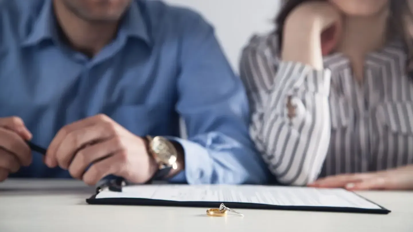 A man and a woman are sitting at a table signing a document.