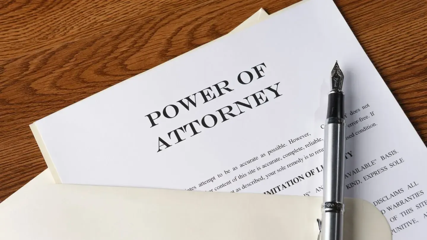 Power of Attorney document with a pen, lying on a wooden surface.