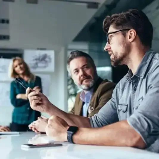a group of people are sitting at a table having a meeting .