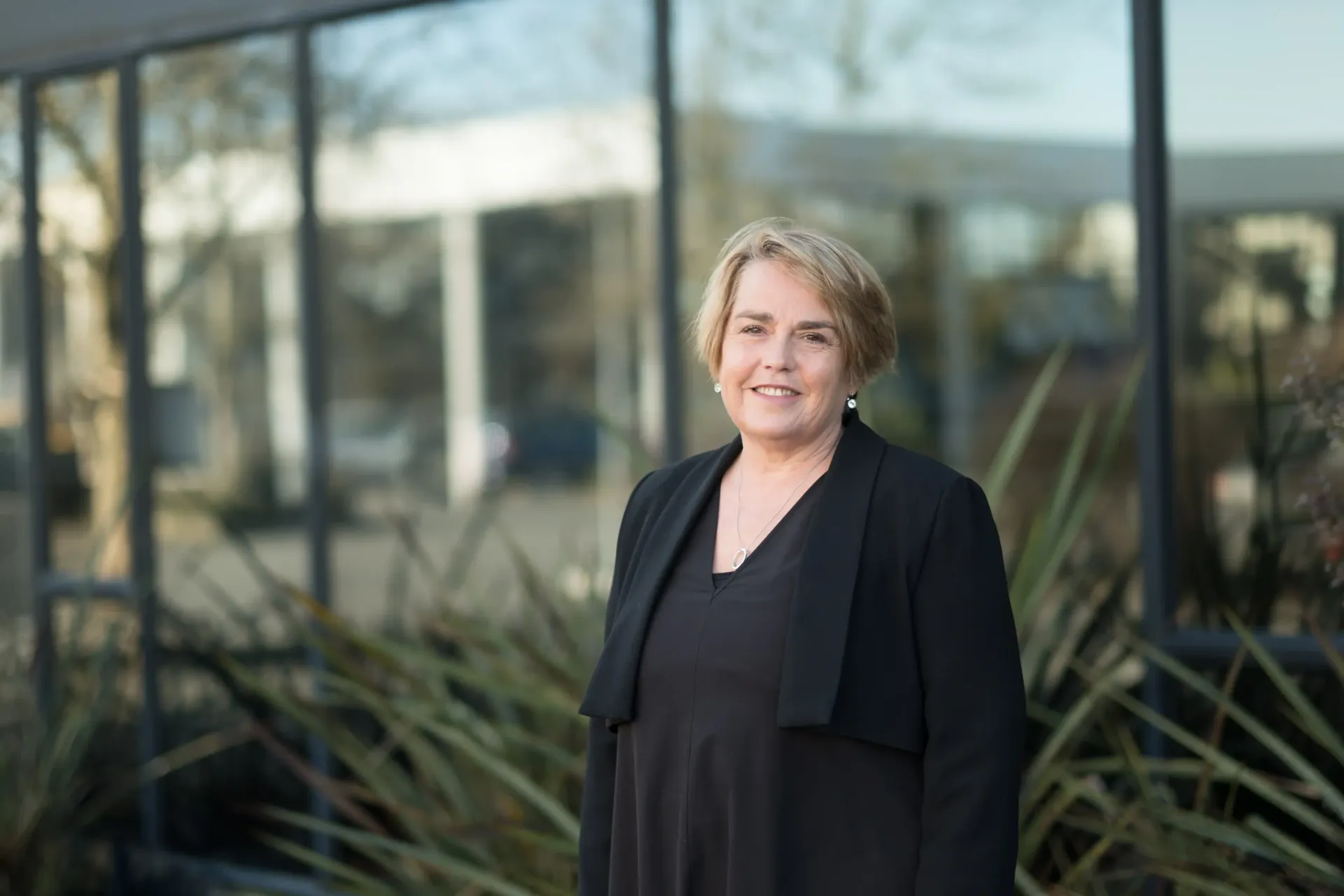 a woman in a black jacket is standing in front of a building .