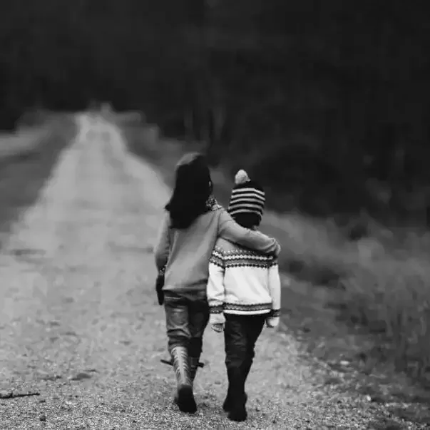 a boy and a girl are walking down a dirt road .