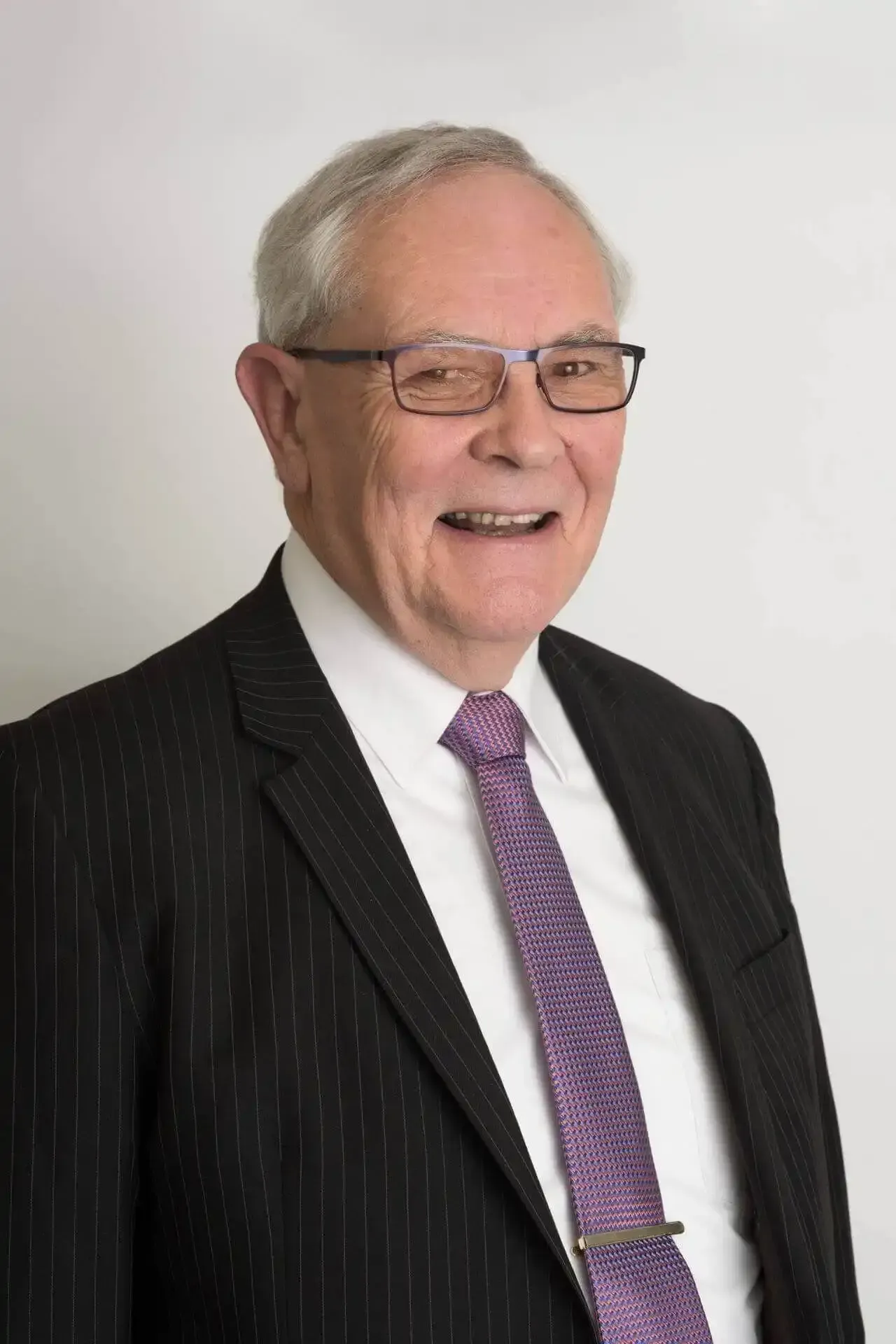 Jim Sutherland in a suit and tie is smiling for the camera