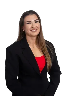 Woman in a black blazer and red top smiles.