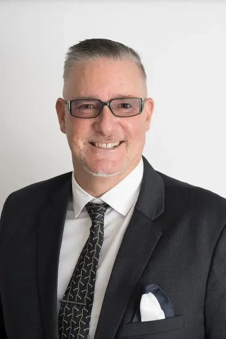 David Houston in a suit and tie is smiling for the camera