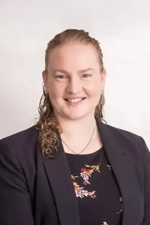 Alison Hill in a black jacket and floral dress is smiling for the camera .