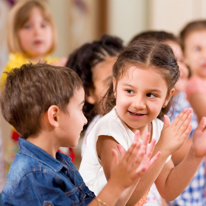 Children clapping happily together in a classroom. Smiling faces, indoors.