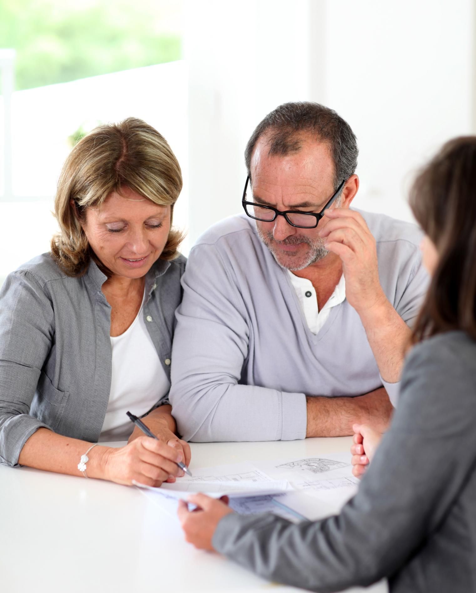 A man and a woman are sitting at a table talking to a woman.