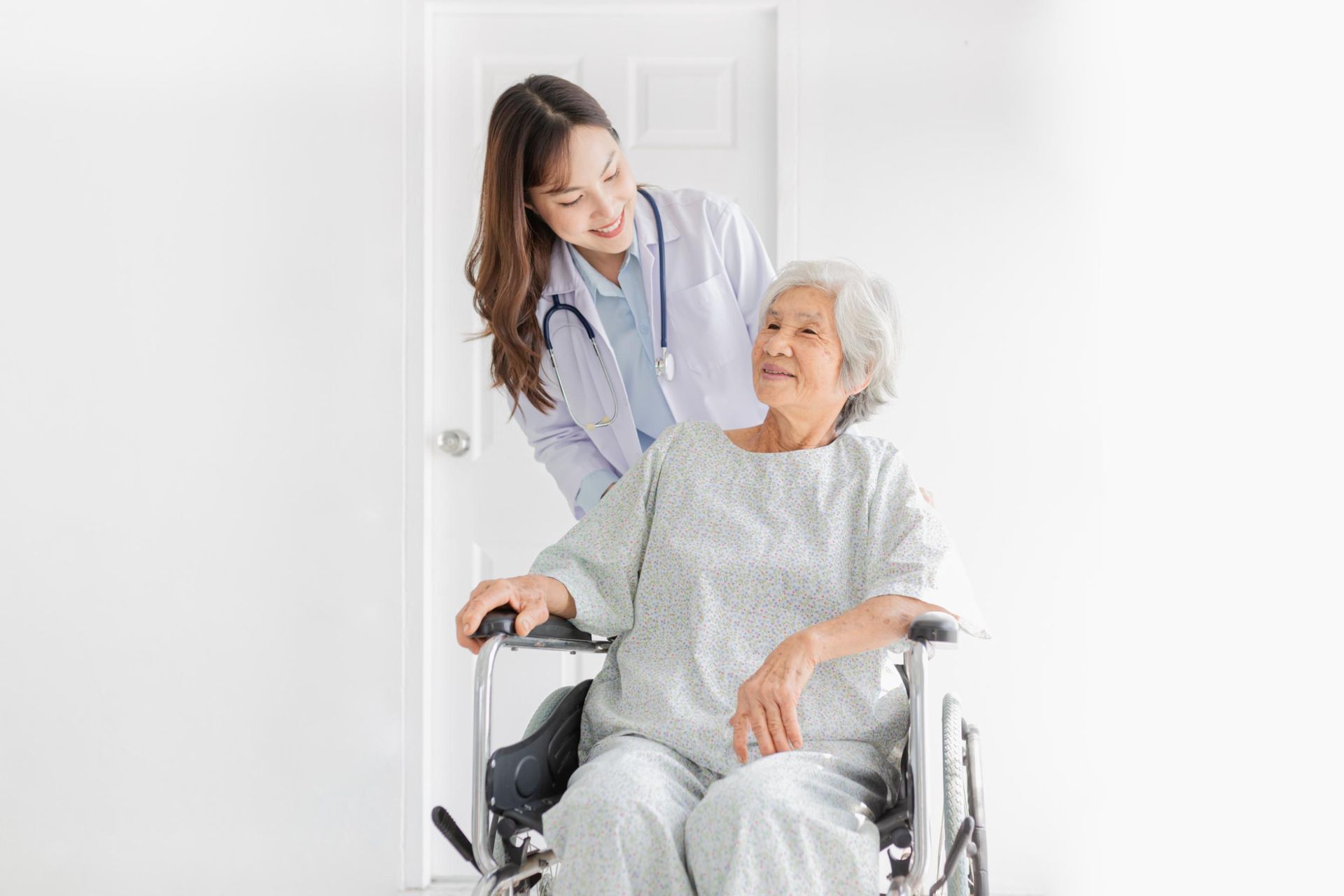 A nurse is helping an elderly woman in a wheelchair.