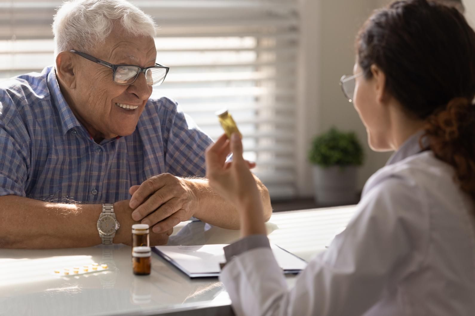 An elderly man is sitting at a table talking to a female doctor.
