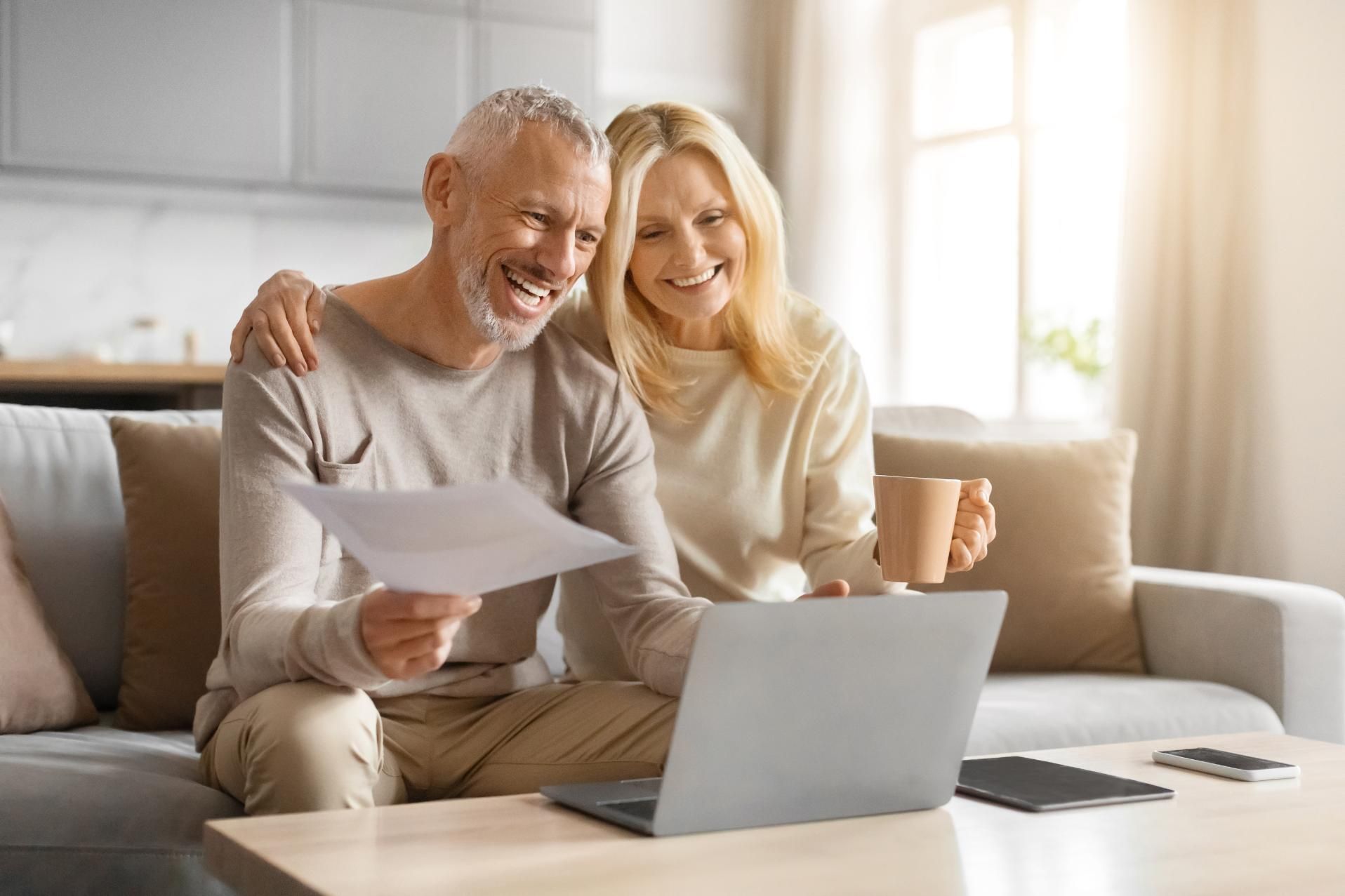 A man and a woman are sitting on a couch looking at a laptop.