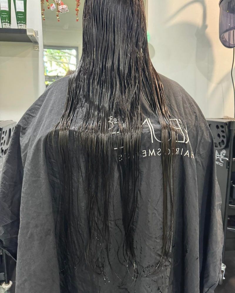 A Woman Is Getting Her Hair Cut In A Salon — Sarina Hair Fashions in Sarina, QLD