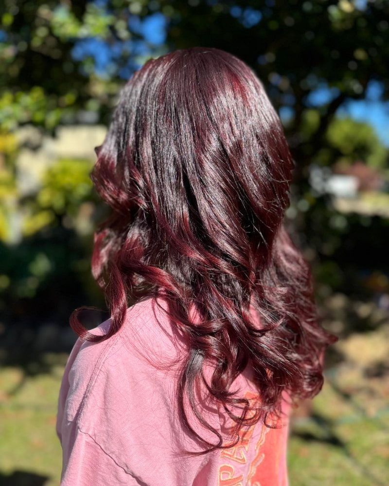 A Woman With Long Dark Red Hair Is Wearing A Pink Hoodie — Sarina Hair Fashions in Sarina, QLD