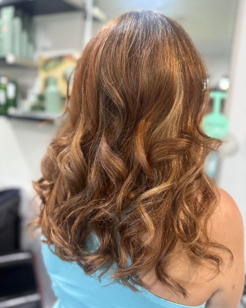 A Woman With Long Brown Hair Is Sitting In A Salon — Sarina Hair Fashions in Sarina, QLD