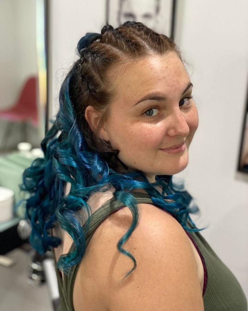 A Woman With Blue Hair Is Smiling And Wearing A Green Tank Top — Sarina Hair Fashions in Sarina, QLD