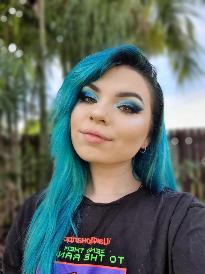 A Woman With Blue Hair And Blue Eyeshadow Is Wearing A Black Shirt — Sarina Hair Fashions in Sarina, QLD