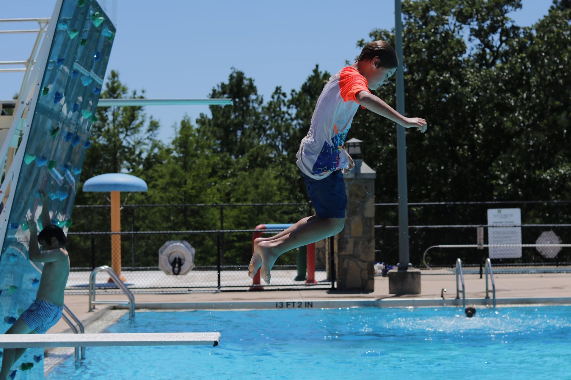 A man is jumping into a pool from a diving board