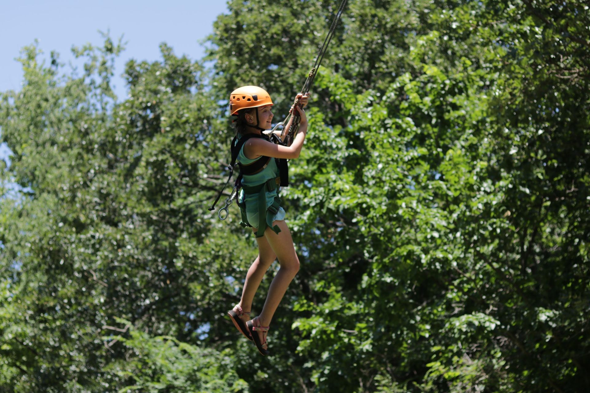 A person is flying through the air on a ropes course.