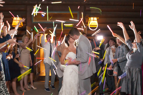 A bride and groom kissing in front of a crowd of people holding glow sticks.