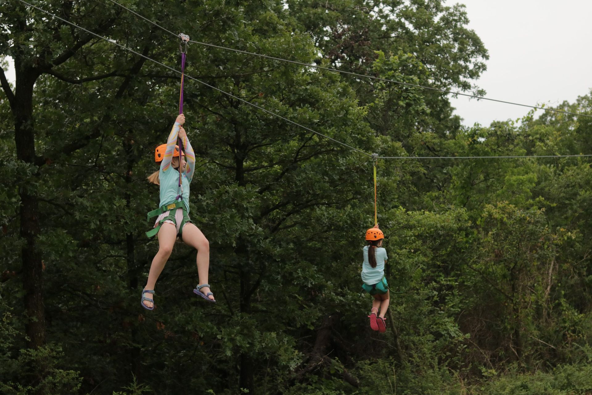 A woman and a child are flying through the air on a zip line.