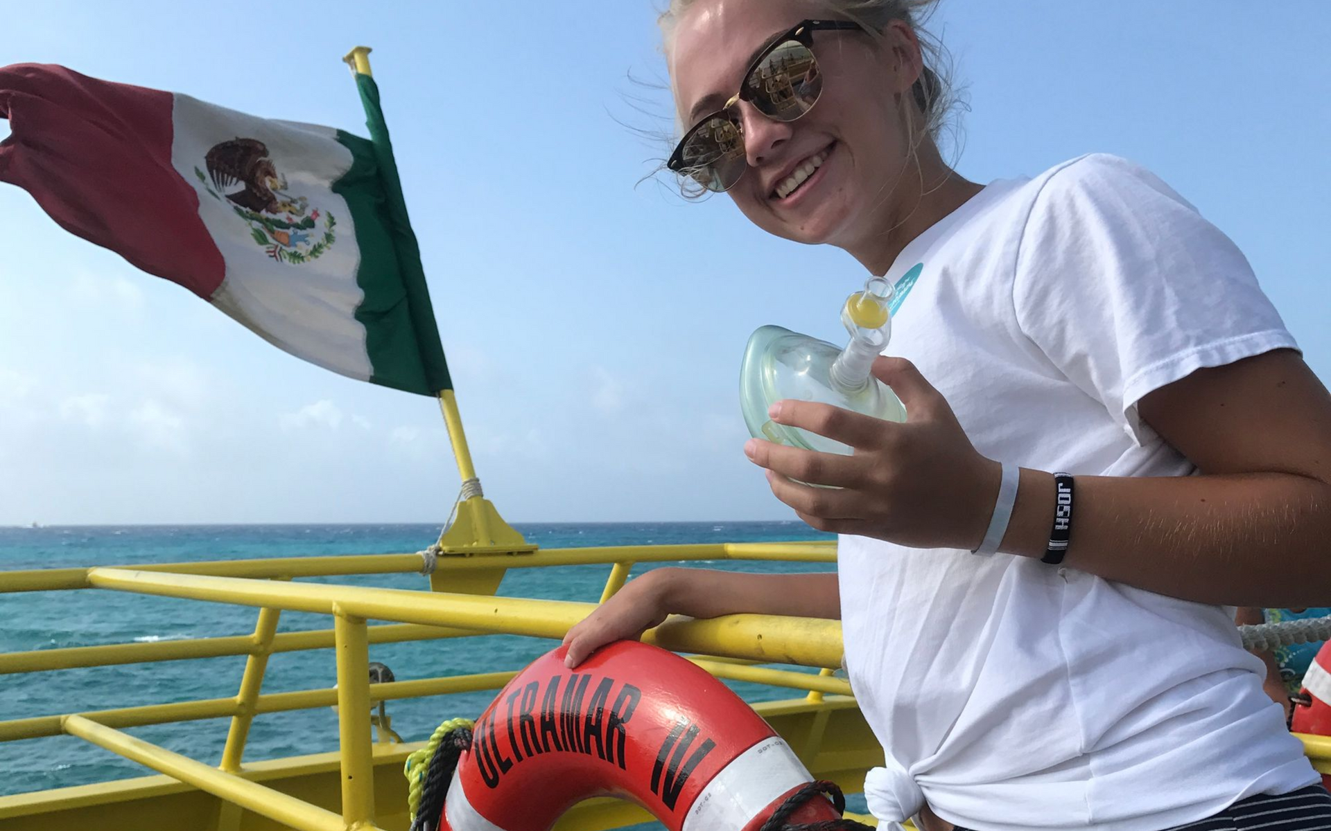 teenager on a boat with the Mexican flag and a life prese