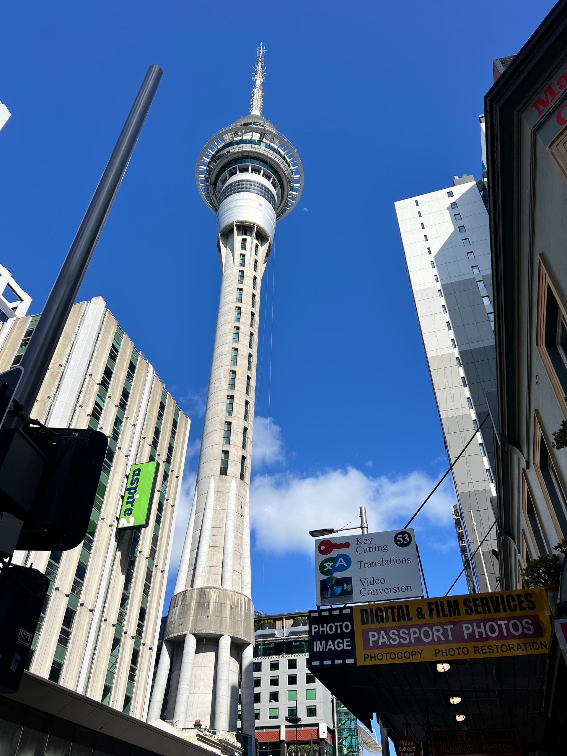 Sky Tower, Auckland, New Zealand, rising above city buildings against a blue sky.