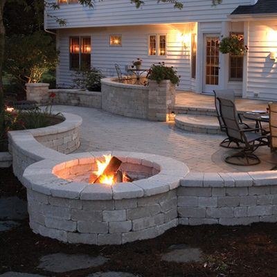 grey stone deck with fire pit outside of a white exterior house
