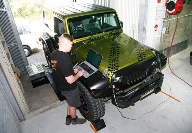 man working on green jeep