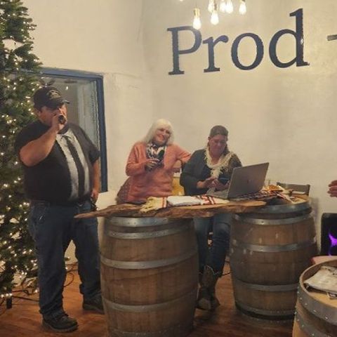 A group of people standing around barrels with the word prod on the wall behind them