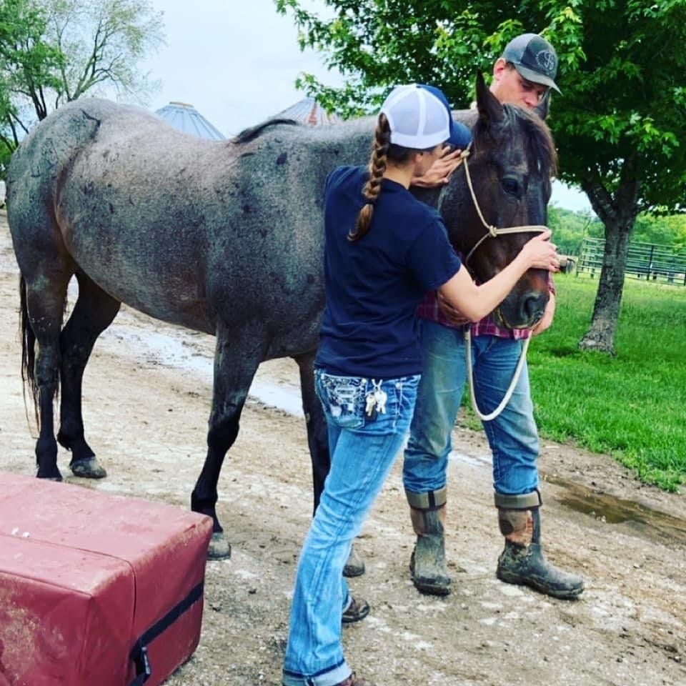 A man and a woman standing next to a horse
