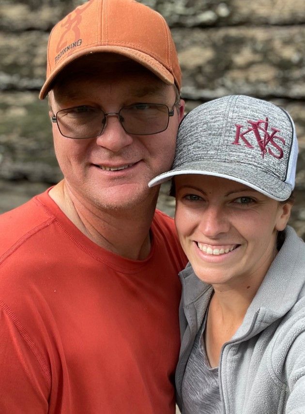 A man and a woman wearing hats are posing for a picture.