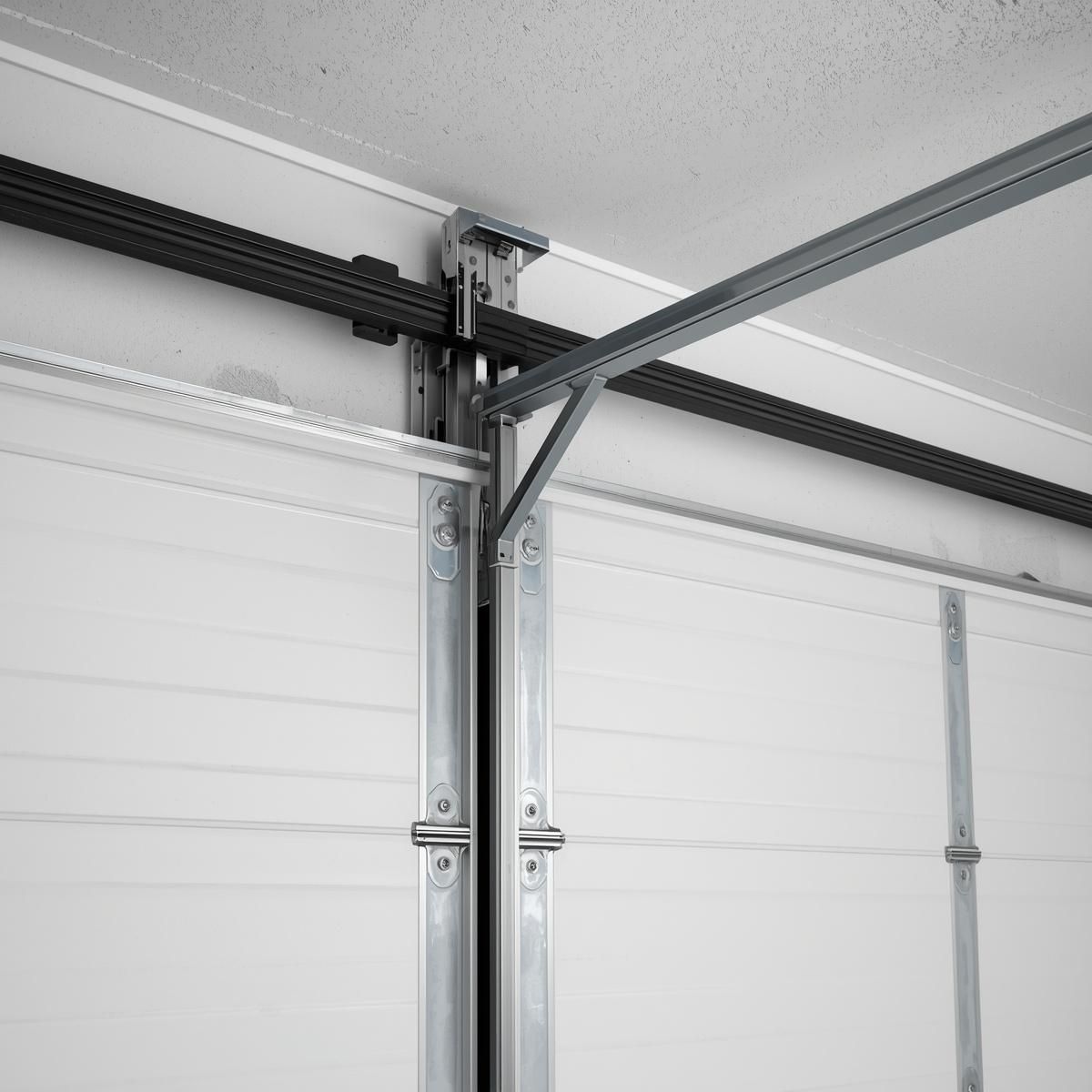 Close-up of a garage door track and opener mechanism on a white sectional garage door