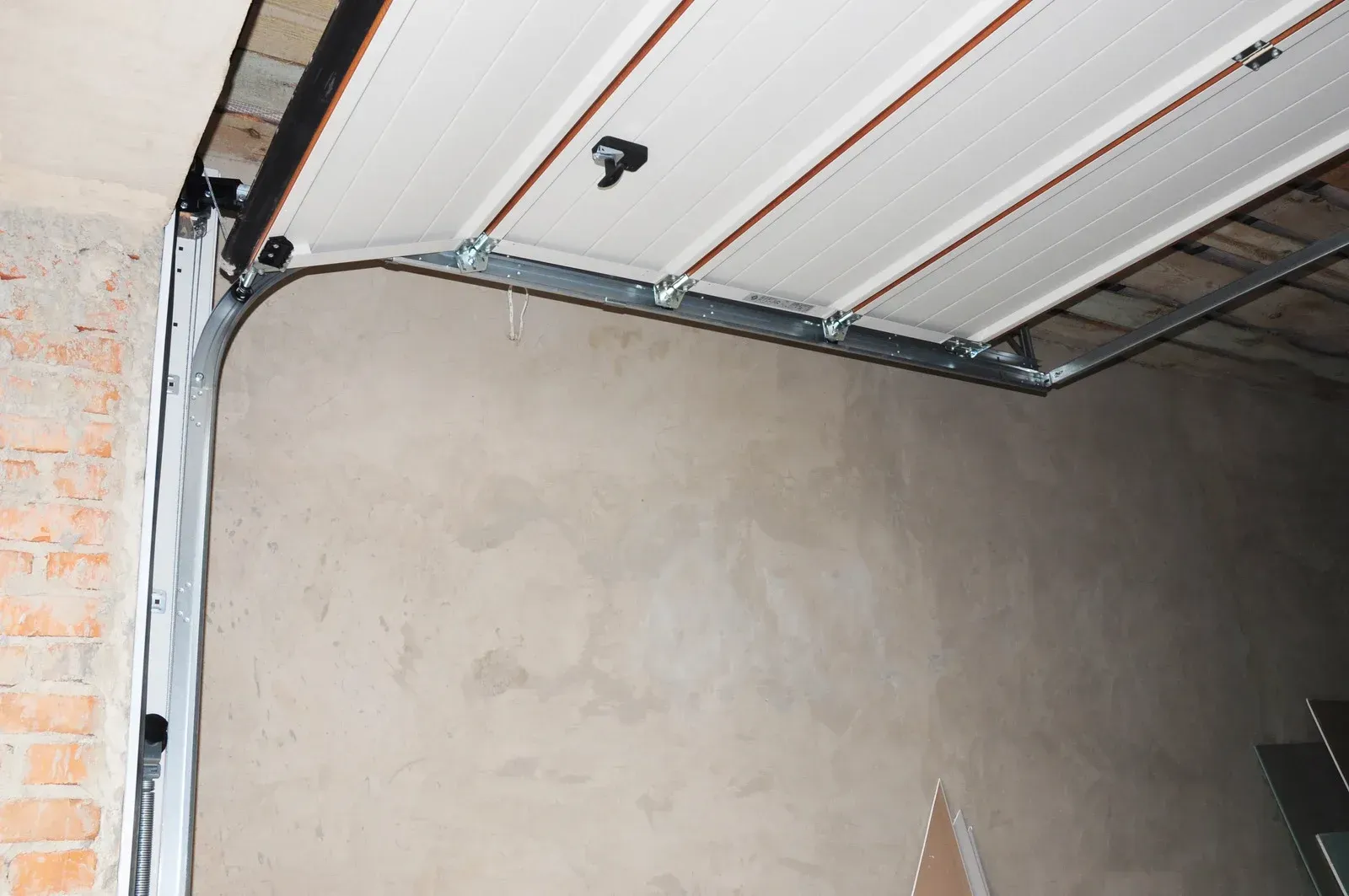 Partially finished garage interior with a gray wall and exposed ceiling tracks