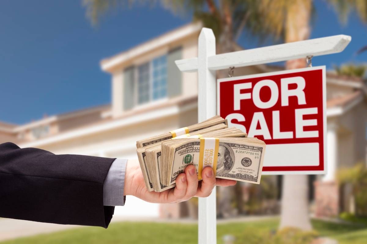 A person holding a wad of money outside a house after a cash offer for a home near Lexington, KY