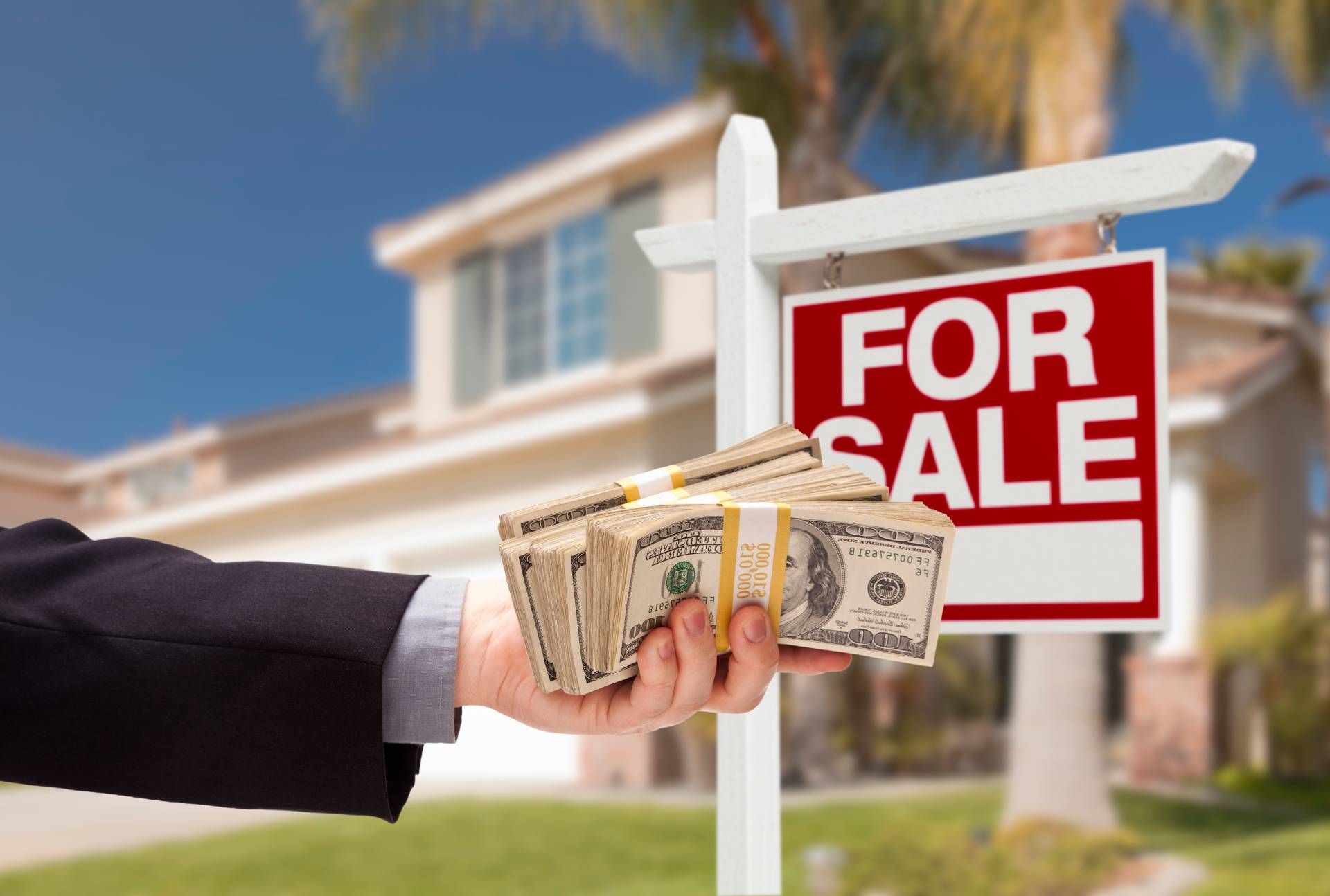 A person holding a wad of money outside a house after a cash offer for a home near Lexington, KY