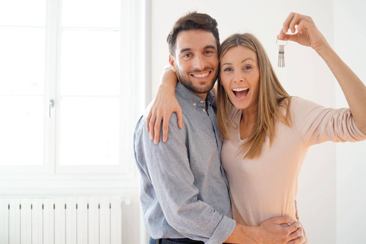 Happy new couple holding keys to a house they just bought near Lexington, KY